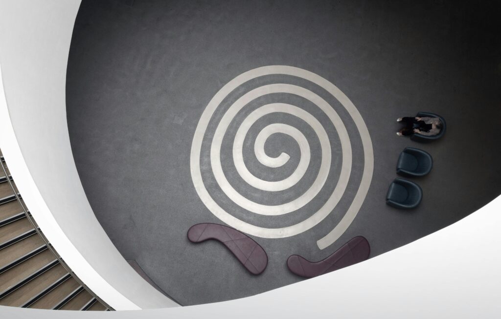 Aerial view of a contemporary spiral pattern in an indoor architectural space with seating.